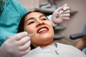 woman during a dental check up with the hands of the dentist by her face