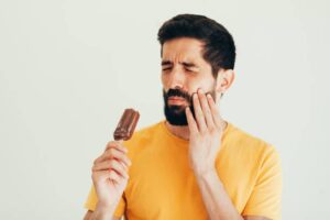 man experiencing tooth sensitivity after eating ice-cream