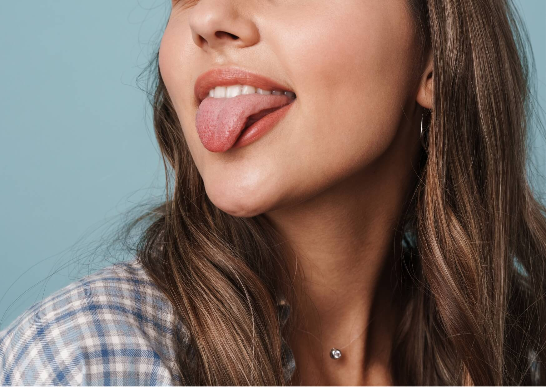 Adult sticking out their tongue to demonstrate tongue mobility during a tongue-tie assessment.
