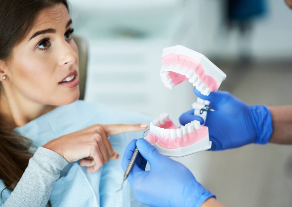 Dentist using a jaw model to explain the causes and treatment options for jaw clicking when chewing.
