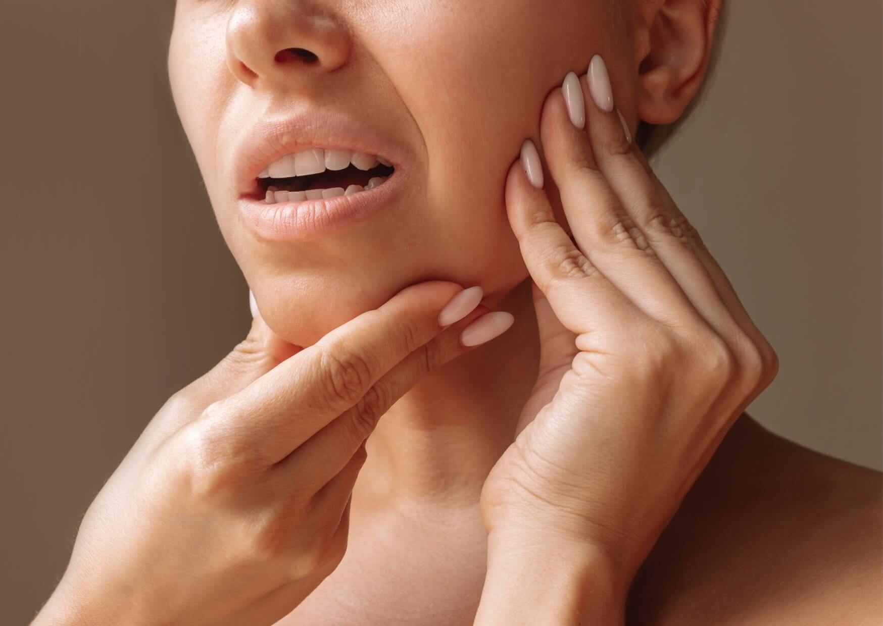 Woman holding her jaw in discomfort, illustrating jaw clicking when chewing and common TMJ-related symptoms.