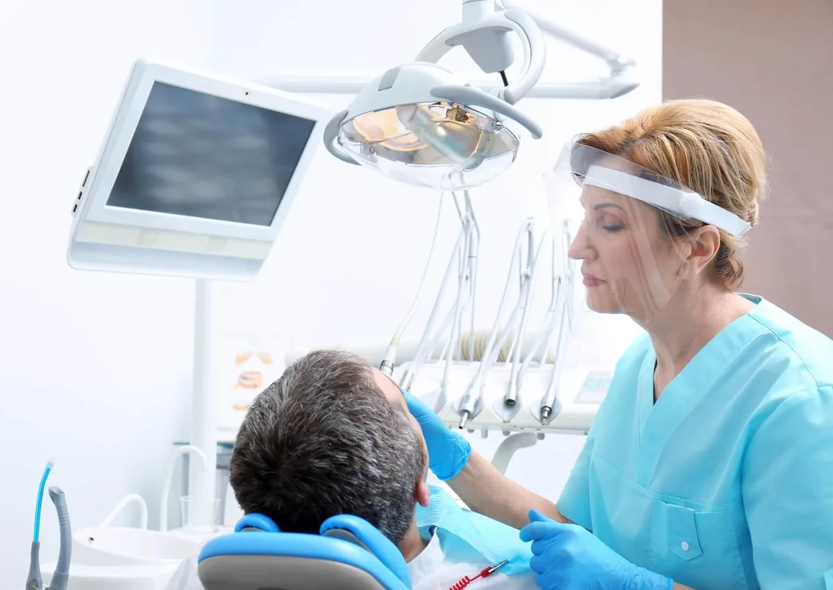 Dentist examining a patient to determine whether a mandibular advancement device may be appropriate for sleep apnea treatment.