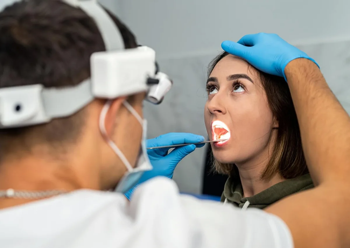 Dentist examining a patient’s mouth for signs of oral thrush and other oral infections.